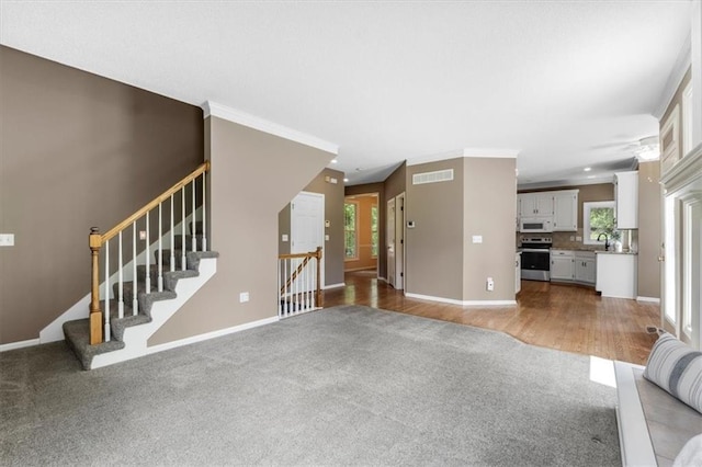 14155 W 147th Ter, Olathe, KS 66062 - unfurnished living room with carpet flooring, baseboards, a sink, stairway, and wood finished floors