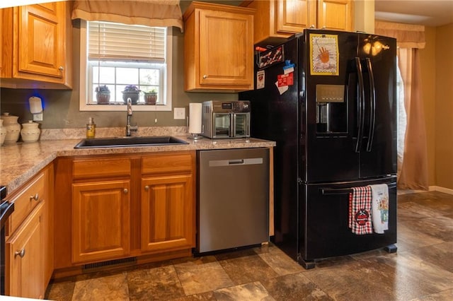 2943 NE Turkey Rd, Breckenridge, MO 64625 - kitchen with stainless steel dishwasher, black fridge, a sink, light countertops, and brown cabinetry