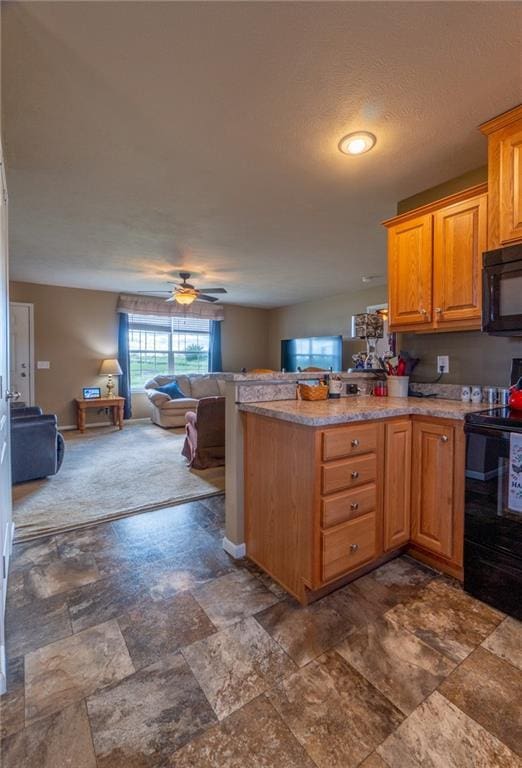 2943 NE Turkey Rd, Breckenridge, MO 64625 - kitchen with black appliances, open floor plan, a peninsula, dark stone finish flooring, and ceiling fan