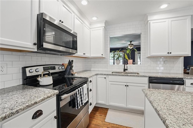 109 N 1st St, Blue Springs, MO 64014 - kitchen featuring appliances with stainless steel finishes, a sink, white cabinetry, a ceiling fan, and backsplash