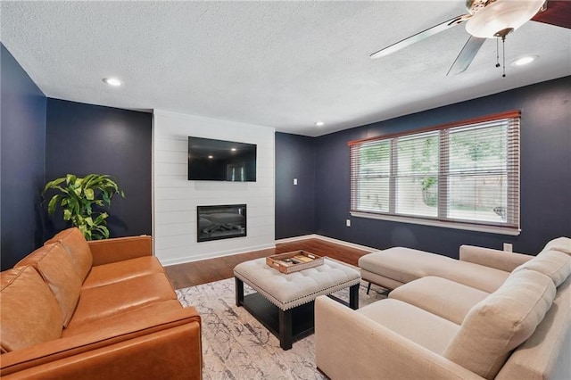 109 N 1st St, Blue Springs, MO 64014 - living room with wood finished floors, a fireplace, a textured ceiling, baseboards, and recessed lighting
