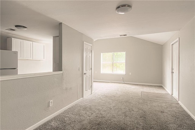 5926 Agnes Ave, Kansas City, MO 64130 - empty room featuring light carpet, vaulted ceiling, baseboards, and a textured wall
