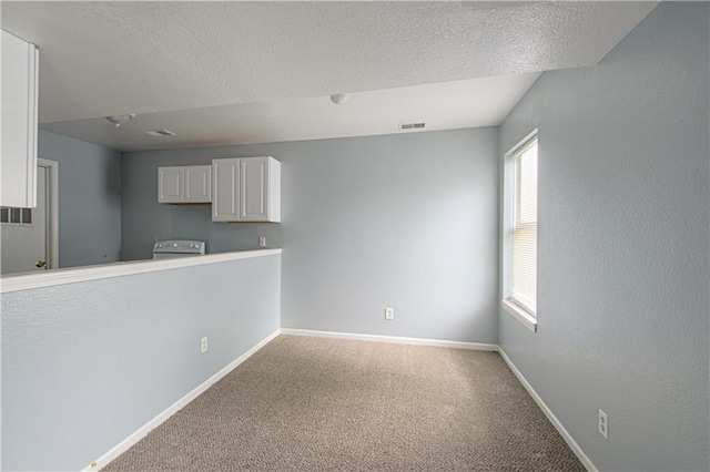 5926 Agnes Ave, Kansas City, MO 64130 - kitchen featuring carpet floors, plenty of natural light, baseboards, white cabinetry, and a textured ceiling