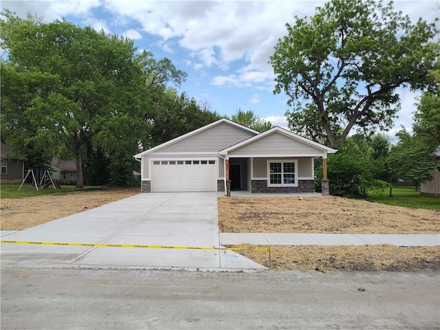 802 E N Main St, Richmond, MO 64085 - view of front of home featuring stone siding, a garage, driveway, and covered porch