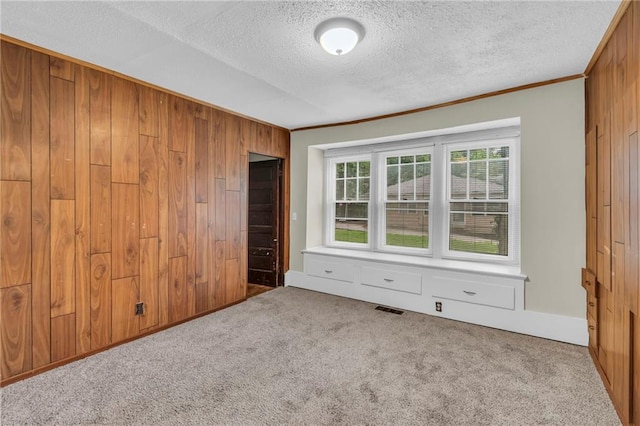 1403 S Sterling Ave, Independence, MO 64052 - unfurnished bedroom featuring wooden walls, a textured ceiling, carpet, and ornamental molding