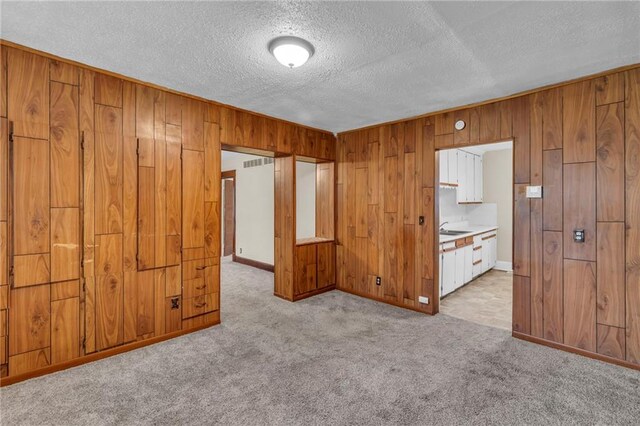 1403 S Sterling Ave, Independence, MO 64052 - carpeted spare room featuring wood walls, a textured ceiling, and baseboards