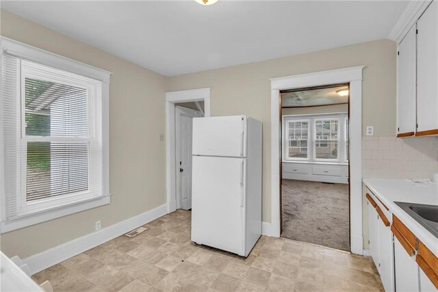 1403 S Sterling Ave, Independence, MO 64052 - kitchen featuring freestanding refrigerator, light countertops, white cabinets, and baseboards