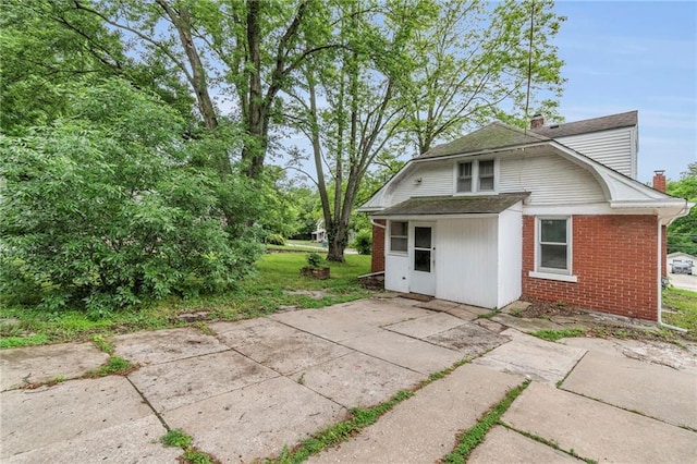 1403 S Sterling Ave, Independence, MO 64052 - back of property with brick siding, a chimney, roof with shingles, and a patio