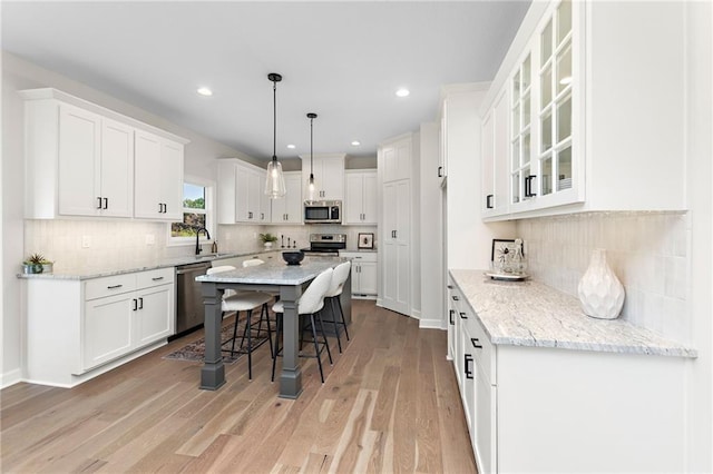 20714 Emerald St, Spring Hill, KS 66030 - kitchen featuring stainless steel appliances, a breakfast bar, white cabinets, a sink, and a kitchen island