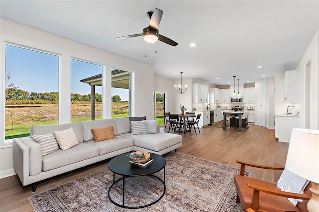 20714 Emerald St, Spring Hill, KS 66030 - living area featuring light wood-style floors, a chandelier, a ceiling fan, baseboards, and recessed lighting