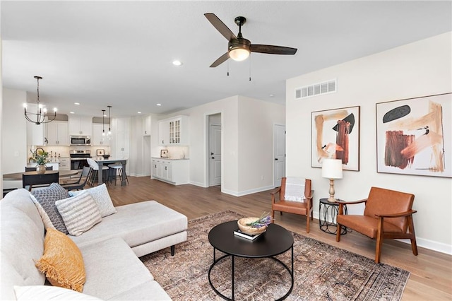 20714 Emerald St, Spring Hill, KS 66030 - living room featuring ceiling fan, light wood-style floors, a chandelier, baseboards, and recessed lighting