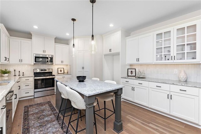 20714 Emerald St, Spring Hill, KS 66030 - kitchen with stainless steel appliances, white cabinets, wood finished floors, decorative backsplash, and glass insert cabinets
