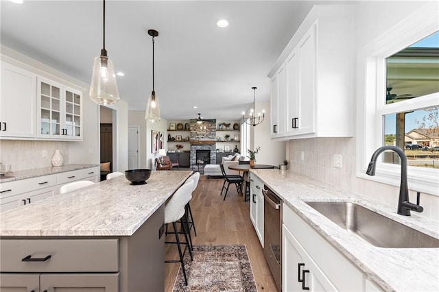 20714 Emerald St, Spring Hill, KS 66030 - kitchen featuring a sink, a glass covered fireplace, wood finished floors, stainless steel dishwasher, and a breakfast bar area