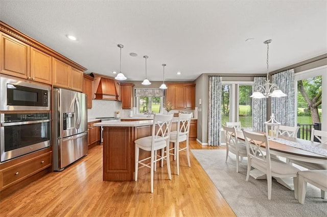 7007 Bell Rd, Shawnee, KS 66217 - kitchen with appliances with stainless steel finishes, custom exhaust hood, a chandelier, brown cabinets, and recessed lighting