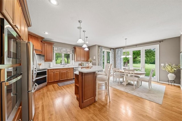 7007 Bell Rd, Shawnee, KS 66217 - kitchen featuring appliances with stainless steel finishes, light countertops, brown cabinetry, a kitchen breakfast bar, and light wood finished floors