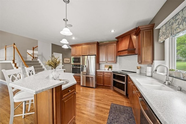 7007 Bell Rd, Shawnee, KS 66217 - kitchen featuring appliances with stainless steel finishes, premium range hood, a sink, light wood-style floors, and a kitchen island