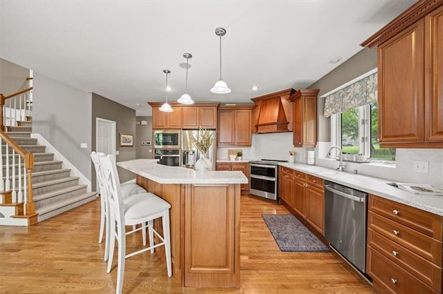 7007 Bell Rd, Shawnee, KS 66217 - kitchen with stainless steel appliances, custom exhaust hood, light wood-type flooring, a sink, and brown cabinetry