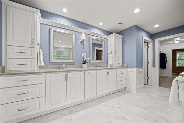 7007 Bell Rd, Shawnee, KS 66217 - bathroom featuring double vanity, marble look tiles, wainscoting, and recessed lighting