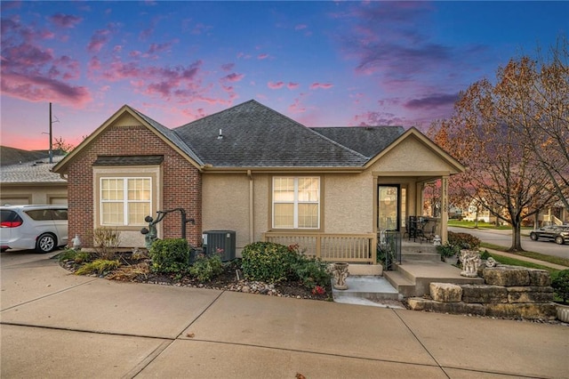 15141 S Symphony Dr Unit 1300, Olathe, KS 66062 - view of front of property featuring central AC, roof with shingles, covered porch, and stucco siding