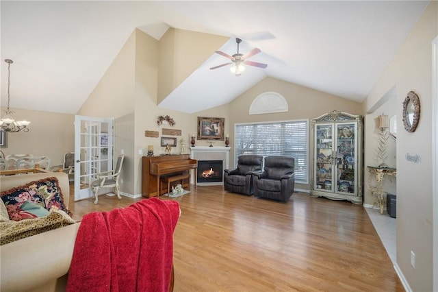 15141 S Symphony Dr Unit 1300, Olathe, KS 66062 - living room with ceiling fan, a glass covered fireplace, wood finished floors, a chandelier, and high vaulted ceiling