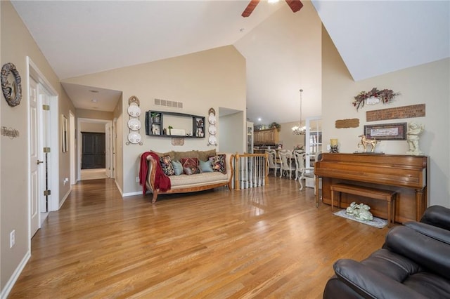 15141 S Symphony Dr Unit 1300, Olathe, KS 66062 - living room featuring ceiling fan, light wood finished floors, a chandelier, high vaulted ceiling, and baseboards