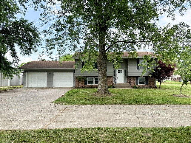 609 N Broadway St, Knob Noster, MO 65336 - bi-level home with concrete driveway, an attached garage, a front yard, and brick siding