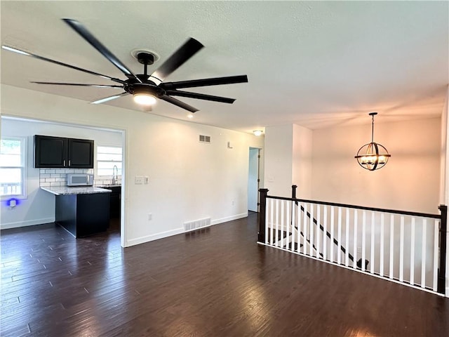 609 N Broadway St, Knob Noster, MO 65336 - unfurnished room with a ceiling fan, a chandelier, baseboards, dark wood-type flooring, and a sink