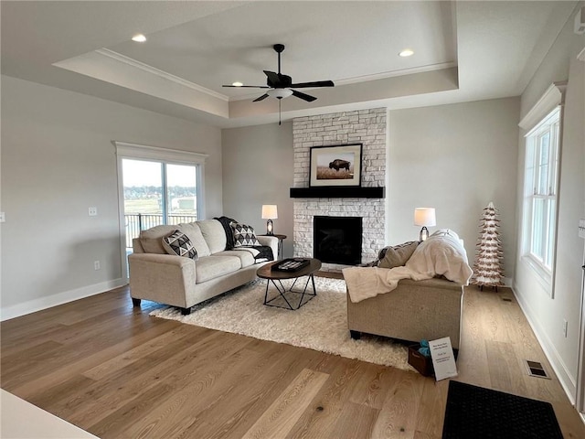 15595 N Sheridan Ct, Basehor, KS 66007 - living room with a tray ceiling, wood finished floors, ceiling fan, a fireplace, and crown molding