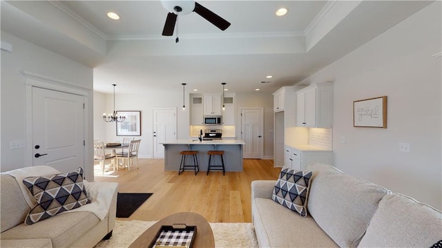15595 N Sheridan Ct, Basehor, KS 66007 - living room featuring a raised ceiling, recessed lighting, light wood finished floors, ornamental molding, and a ceiling fan