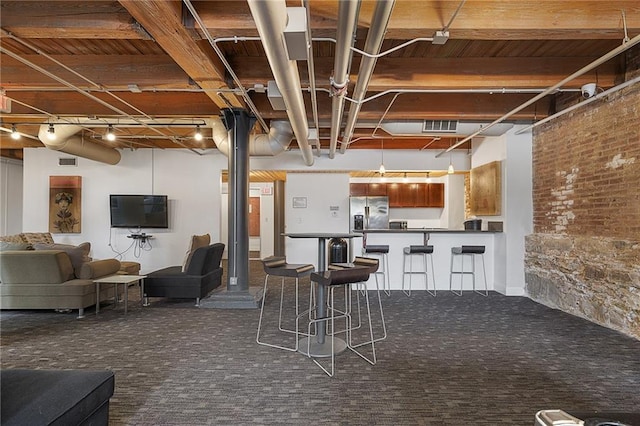 700 Broadway Blvd Unit 210, Kansas City, MO 64105 - kitchen featuring dark carpet, dark countertops, open floor plan, stainless steel fridge, and a kitchen breakfast bar