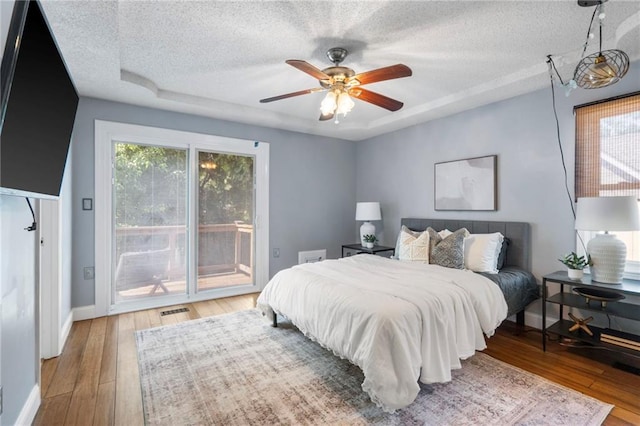 16011 W 149th Ter, Olathe, KS 66062 - bedroom with access to exterior, a textured ceiling, wood-type flooring, a raised ceiling, and a ceiling fan
