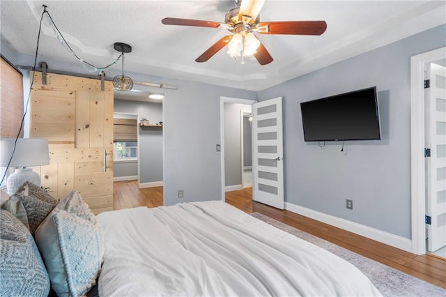16011 W 149th Ter, Olathe, KS 66062 - bedroom with wood finished floors, a barn door, a ceiling fan, and a spacious closet