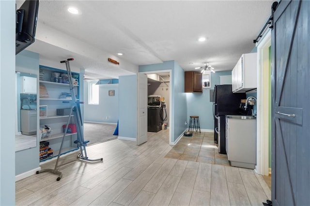 16011 W 149th Ter, Olathe, KS 66062 - kitchen with a barn door, light wood finished floors, recessed lighting, dark countertops, and white cabinetry
