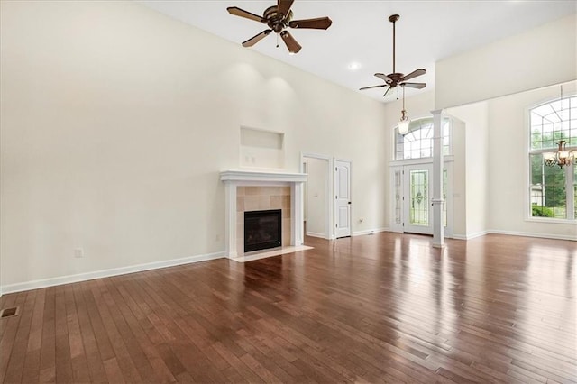 906 Cheatham Ct, Warrensburg, MO 64093 - unfurnished living room featuring ceiling fan, hardwood / wood-style flooring, a tile fireplace, a towering ceiling, and baseboards