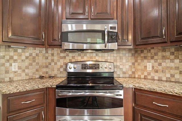 906 Cheatham Ct, Warrensburg, MO 64093 - kitchen with stainless steel appliances, decorative backsplash, light stone counters, and dark brown cabinetry