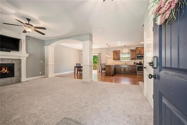 5021 NW Timberline Dr, Riverside, MO 64150 - living area featuring carpet floors, ceiling fan, baseboards, a fireplace, and decorative columns