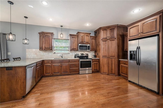 5021 NW Timberline Dr, Riverside, MO 64150 - kitchen with stainless steel appliances, a peninsula, a sink, light wood-type flooring, and backsplash