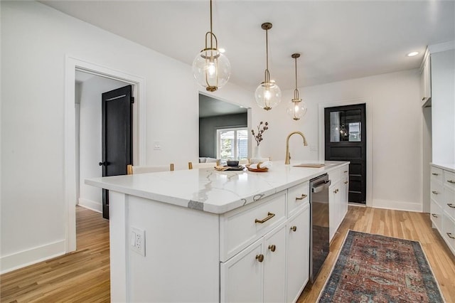 4804 Jarboe St, Kansas City, MO 64112 - kitchen with a sink, light wood-type flooring, stainless steel dishwasher, a kitchen island with sink, and white cabinetry