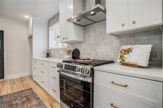 4804 Jarboe St, Kansas City, MO 64112 - kitchen with stainless steel gas range oven, wall chimney exhaust hood, light wood finished floors, light stone countertops, and white cabinets