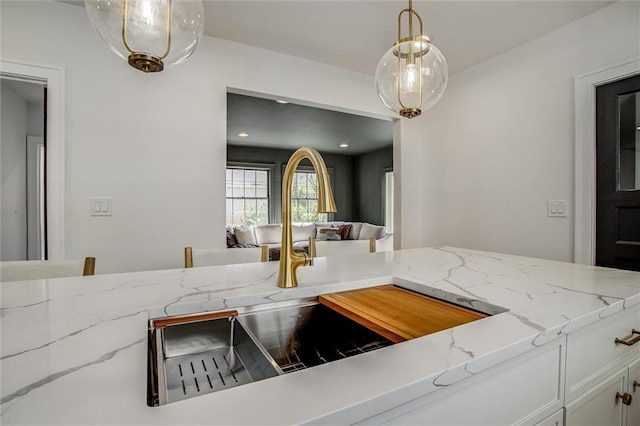 4804 Jarboe St, Kansas City, MO 64112 - kitchen with a sink, light stone counters, decorative light fixtures, white cabinets, and open floor plan