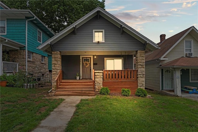 4421 Tracy Ave, Kansas City, MO 64110 - bungalow-style house featuring covered porch, a front lawn, and stone siding