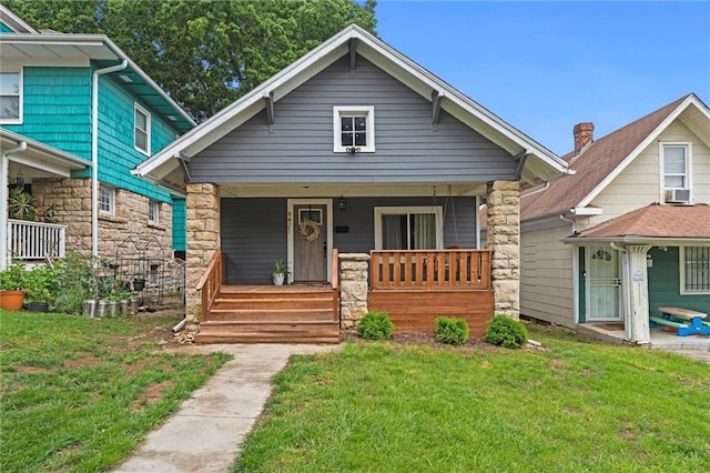 4421 Tracy Ave, Kansas City, MO 64110 - view of front of house with a porch, a front lawn, and stone siding