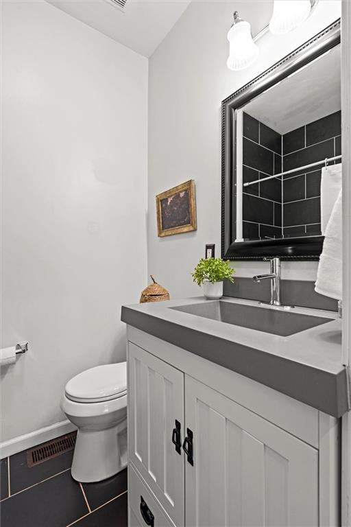4421 Tracy Ave, Kansas City, MO 64110 - bathroom featuring vanity, toilet, baseboards, tile patterned flooring, and curtained shower