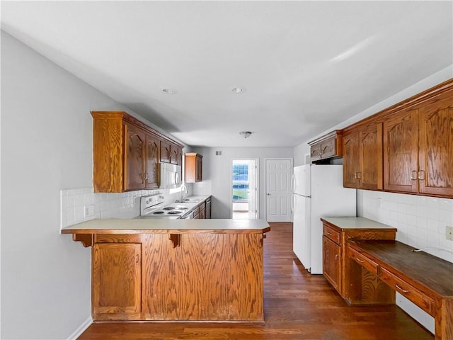 18100 E 11th Terrace Ct N, Independence, MO 64056 - kitchen with white appliances, a sink, dark wood-type flooring, a peninsula, and decorative backsplash