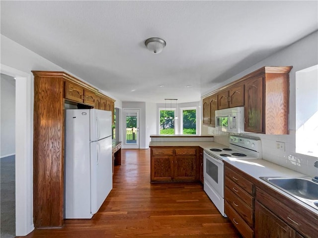 18100 E 11th Terrace Ct N, Independence, MO 64056 - kitchen featuring white appliances, a peninsula, a sink, dark wood finished floors, and light countertops