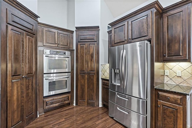 16904 S Bradley Dr, Olathe, KS 66062 - kitchen featuring appliances with stainless steel finishes, tasteful backsplash, dark stone countertops, and dark brown cabinets