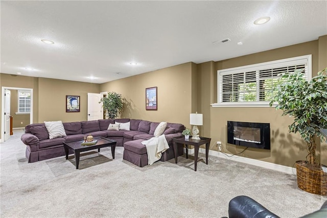 16904 S Bradley Dr, Olathe, KS 66062 - carpeted living room featuring a glass covered fireplace, healthy amount of natural light, a textured ceiling, and recessed lighting