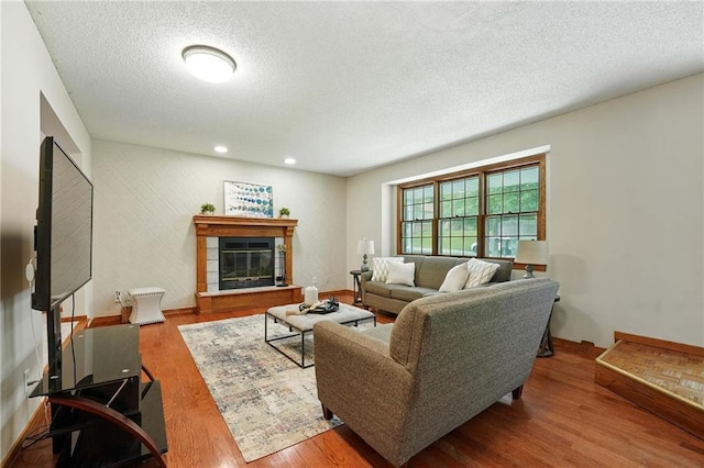 8025 Woodstone St, Lenexa, KS 66219 - living area with wood finished floors, a textured ceiling, and a glass covered fireplace
