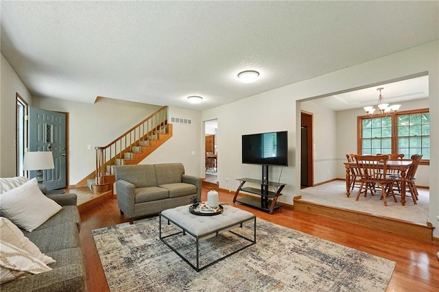 8025 Woodstone St, Lenexa, KS 66219 - living room with stairs, wood finished floors, a chandelier, and a textured ceiling