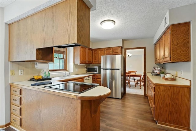 8025 Woodstone St, Lenexa, KS 66219 - kitchen featuring stainless steel appliances, a peninsula, wood finished floors, light countertops, and a textured ceiling